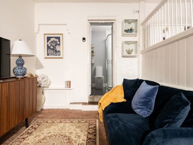 A living room with a sofa and a view of a bathroom door at Stable in Blandford Forum