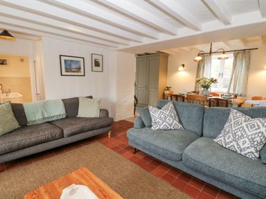 A living room with two sofas and a dining table with flowers at Dyffryn Cottage in Aberporth