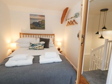 A bedroom with a double bed with pillows and folded towels and bedside lamps at Dyffryn Cottage in Aberporth