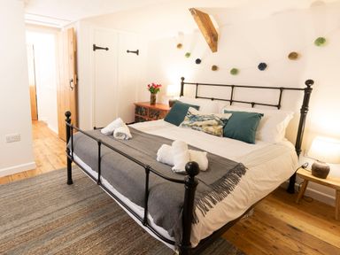A bedroom with a black metal bed frame white bedding and rolled towels on the bed Dyffryn Cottage Aberporth