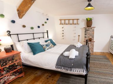 A bedroom with a black metal bed frame a chest of drawers next to the bed and a wooden floor at Dyffryn Cottage in Aberporth