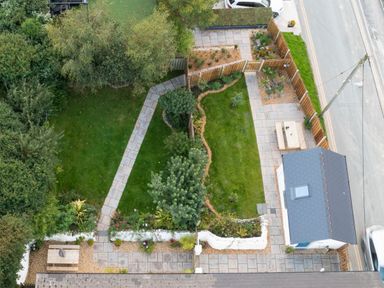 A fenced garden with grass paths bushes benches and a small building next to a road at Dyffryn Cottage in Aberporth