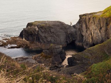 A rocky coastal area with a person fishing on a cliff at Dyffryn Cottage in Aberporth