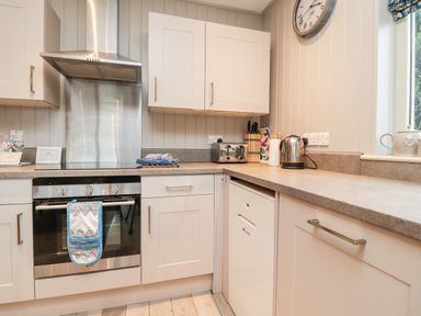 A kitchen with an oven a toaster a kettle and white cabinets at Beech Lodge in Goosnargh