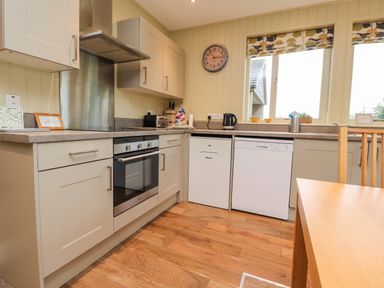 A kitchen with cabinets oven dishwasher kettle and a dining table at Oak Lodge in Goosnargh