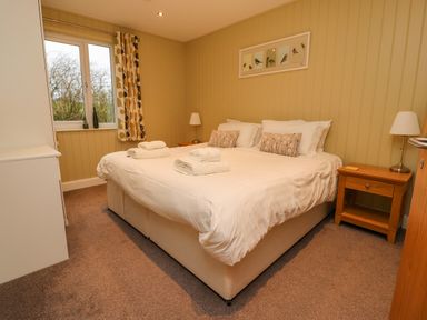 A bedroom with a double bed white linens bedside tables and a window with curtains at Oak Lodge in Goosnargh