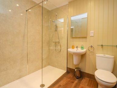 A bathroom with a glass shower enclosure a wall-mounted sink and a toilet at Oak Lodge in Goosnargh