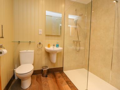A bathroom with a toilet a sink a mirror and a glass-enclosed shower area at Oak Lodge in Goosnargh