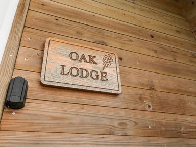 A wooden sign reading Oak Lodge mounted on a wooden exterior wall at Oak Lodge in Goosnargh