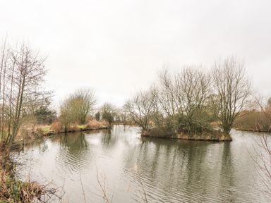 A body of water with small docks and trees along the banks at Oak Lodge in Goosnargh