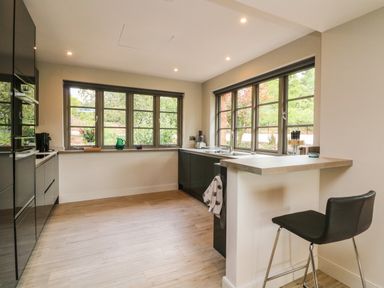 A kitchen with black cabinets wooden floor and large windows at Court Lodge Bathealton near Wiveliscombe