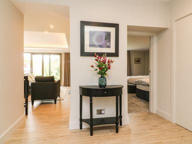 A hallway with a black console table holding a blue vase with flowers and a framed artwork above at Court Lodge in Bathealton near Wiveliscombe