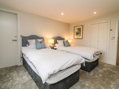 A bedroom with two single beds bedside lamps and a framed picture on the wall at Court Lodge in Bathealton near Wiveliscombe
