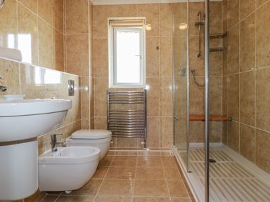 A bathroom with a sink bidet toilet shower and heated towel rack with beige tiles at Newquay Tamarisk Lodge on the Gannel in Newquay