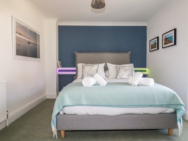 A bedroom with a bed with white linens and a light blue blanket at Newquay Tamarisk Lodge on the Gannel in Newquay