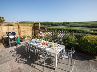 An outdoor patio with a dining table set for breakfast and a barbecue grill at Newquay Tamarisk Lodge on the Gannel in Newquay