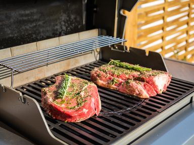 Two raw steaks with herbs on a gas grill outdoors at Newquay Tamarisk Lodge on the Gannel in Newquay