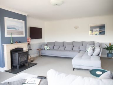 A living room with a sofa and television at Newquay Tamarisk Lodge on the Gannel Newquay
