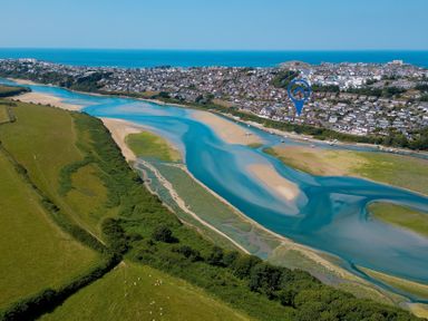 An aerial view of a river and houses near the ocean at Newquay Tamarisk Lodge on the Gannel, Newquay