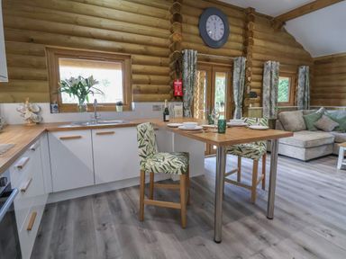 A kitchen and dining area with wooden floors and log walls at Redwood Lodge in Ellesmere