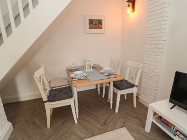 A dining area with a table set for four under a staircase at Cosy Cottage in Amble