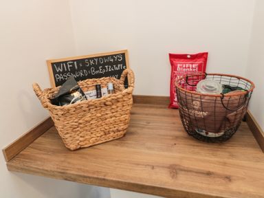 A wooden shelf with two baskets and a fire blanket in a corner at Cosy Cottage in Amble