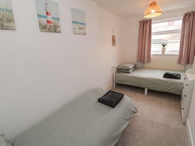 A bedroom with two single beds and pastel green bedding at Cosy Cottage in Amble