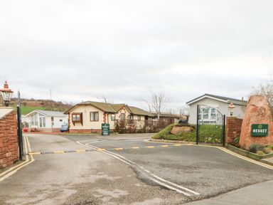 The entrance to a gated residential area with houses a road and a sign reading Hesket at Rosies Zen Den in High Hesket near Armathwaite