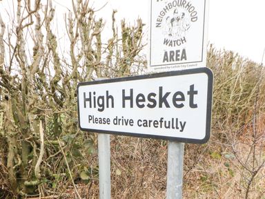 A road sign reading High Hesket Please drive carefully with a neighbourhood watch sign above in a rural setting at Rosie's Zen Den in High Hesket near Armathwaite