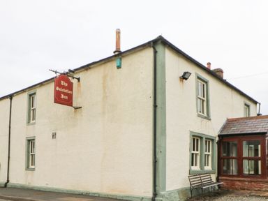 An exterior view of a building with a red sign reading The Salutation Inn and a bench outside