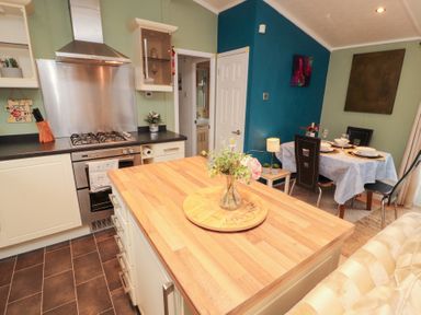 A kitchen with a gas stove and dining table at Rosie's Zen Den in High Hesket near Armathwaite