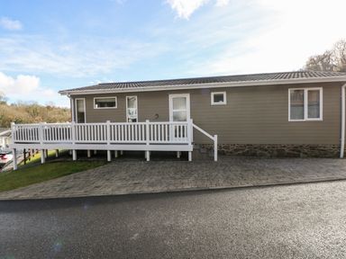 Exterior view of a single story house with a white railing and paved driveway at Lodge 53 in Stepaside near Kilgetty