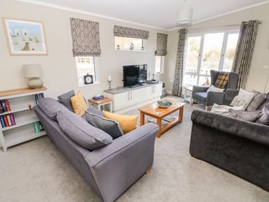 A living room with sofas armchair coffee table and television at Lodge 53 Stepaside near Kilgetty
