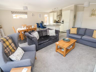 An open plan living room with two sofas an armchair a coffee table and a dining table with chairs at Lodge 53 Stepaside near Kilgetty