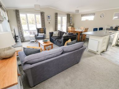 A living room with sofas and armchair next to a dining table and kitchen island at Lodge 53 Stepaside near Kilgetty