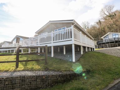 A row of raised lodges with white railings on a grassy slope at Lodge 53 in Stepaside near Kilgetty