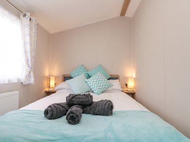 A bedroom with a bed pillows side tables lamps and rolled towels at Rowan Court 2 in Cayton