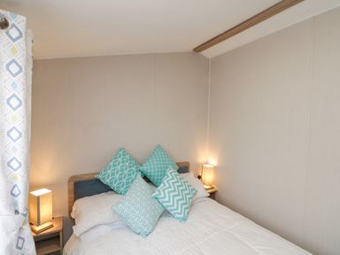 A bedroom with a bed with blue patterned pillows and two bedside tables with lamps at Rowan Court 2 in Cayton