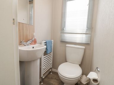 A bathroom with a toilet sink towel and window blinds at Rowan Court 2 in Cayton