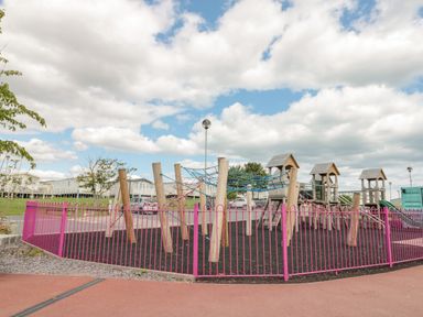 An outdoor playground with climbing structures and rope nets surrounded by a pink fence at Rowan Court 2 in Cayton