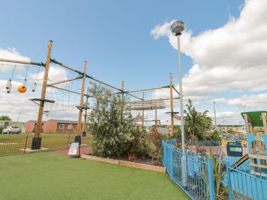 An outdoor playground with climbing structures and a blue fenced area at Rowan Court 2 in Cayton