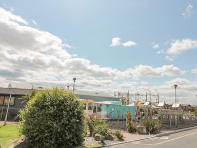 An outdoor playground area with play structures and seating near a building under a partly cloudy sky at Rowan Court 2 in Cayton