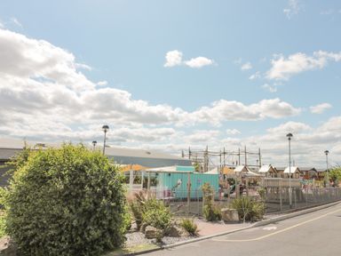 An outdoor playground with wooden play structures under a partly cloudy sky at Rowan Court 2 in Cayton