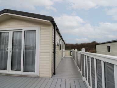 Exterior view of a mobile home with a sliding glass door and a gray deck with white railing at Rowan Court 2 in Cayton