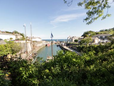 A small harbor with boats docked along stone walls next to buildings and greenery at Sea View in St Austell
