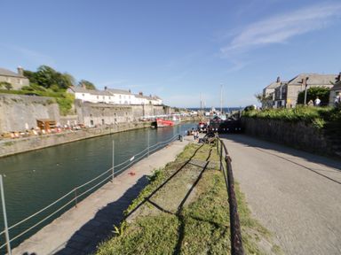 A harbor with boats docked and a pathway alongside water at Sea View in St Austell