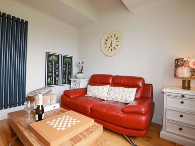 A living room with a red sofa and coffee table at Sea View in St Austell