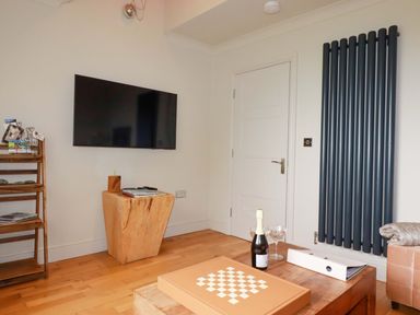 A living room with a television and a wooden stool at Sea View in St Austell