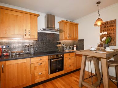 A kitchen with wooden cabinets and a table at Sea View in St Austell