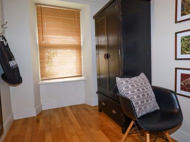A hallway with a wardrobe and chair at Sea View in St Austell